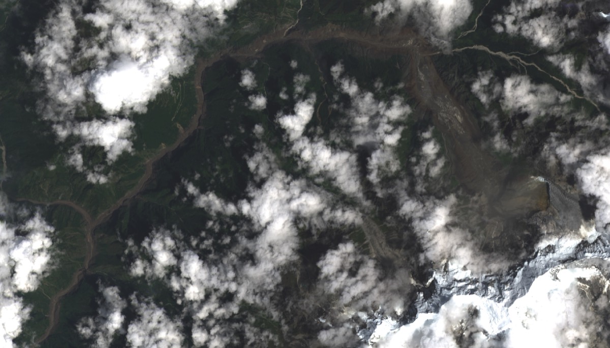Satellite view of the same valley on the day of the flood, a wide band of debris scouring the valley floor
